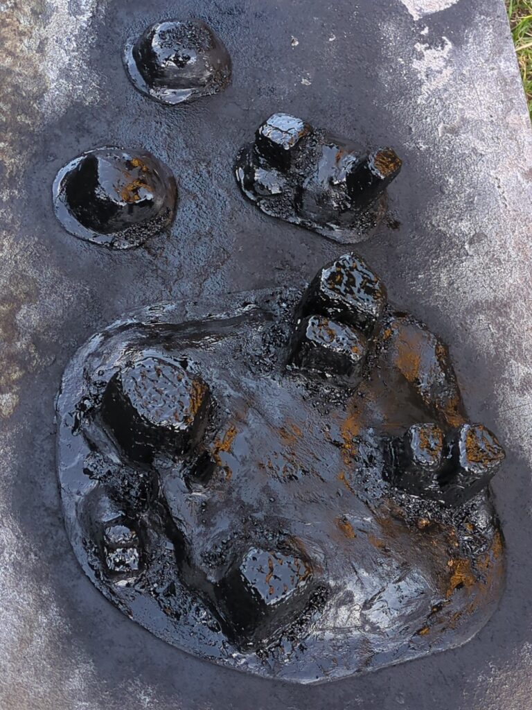 Several plaster hills sit on a scrap piece of wood. They are have been undercoated with black spraypaint