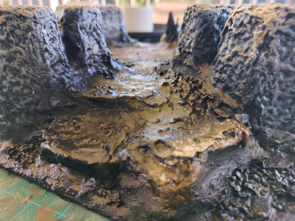 A close up of a plaster mountain, the plaster has been undercoated with black airbrush undercoat.