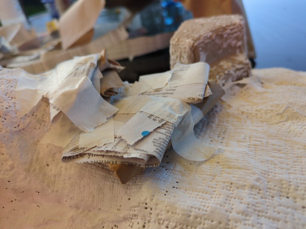 A close up of a plaster hill. Several small balls of newspaper and packing paper have been added to begin converting the incline into a set of ledges.
