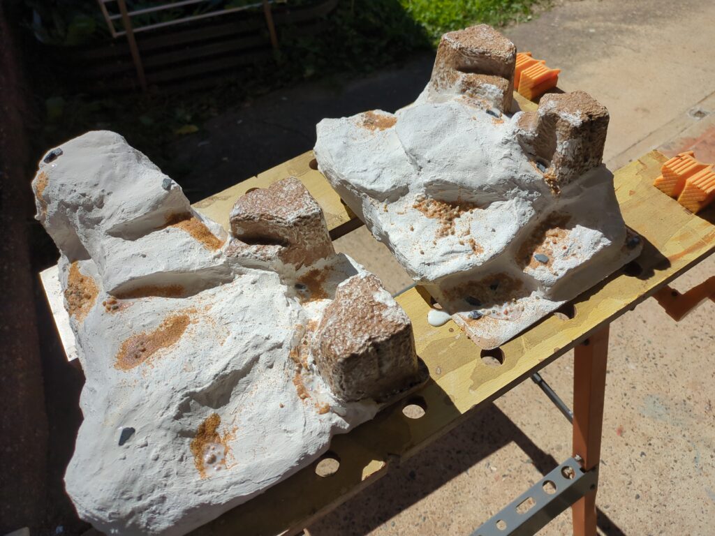 Two plaster bandage hills sit drying outside on a hobby horse.