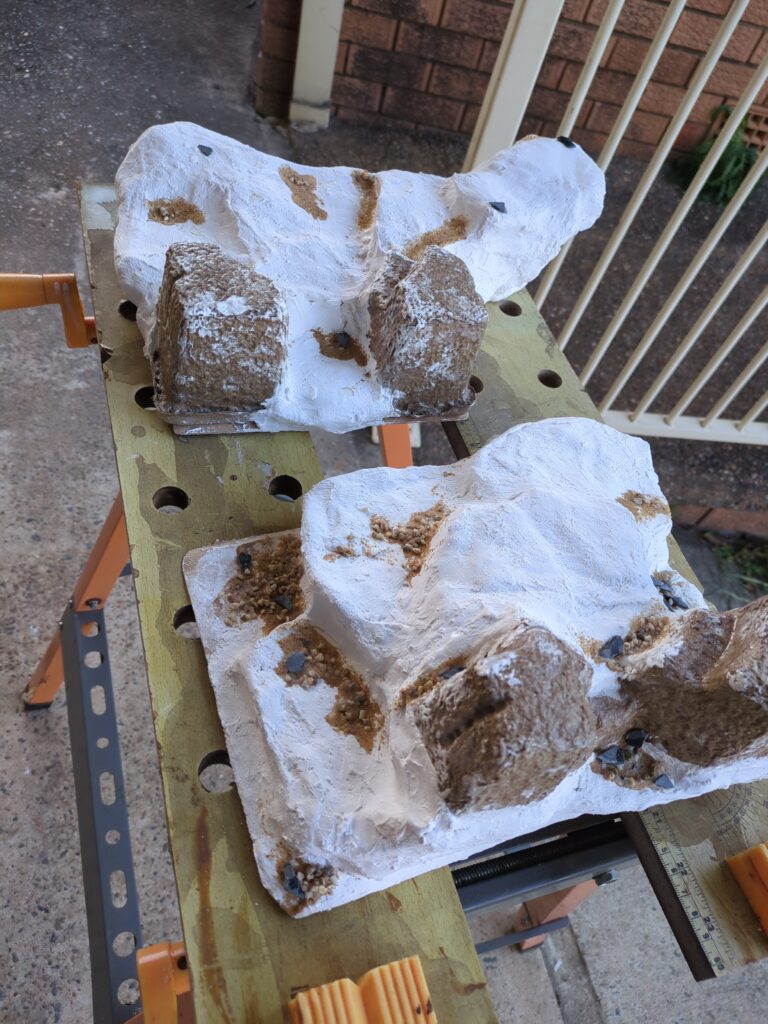Two plaster bandage hills sit drying outside on a hobby horse.