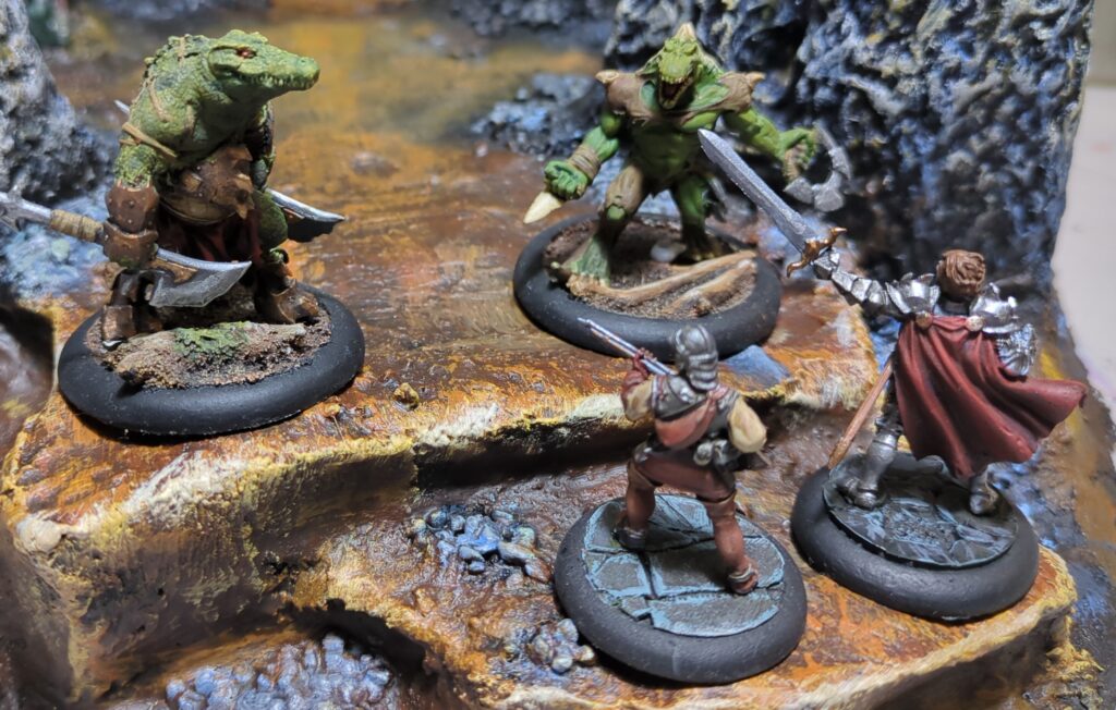 Two Hell Dorado conquistadors attempt to scale a mountain cliff. Atop the cliff a humanoid alligator warrior and a lizard man stand ready to repel them.